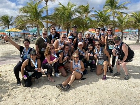 Team on the beach under palm trees with event medals